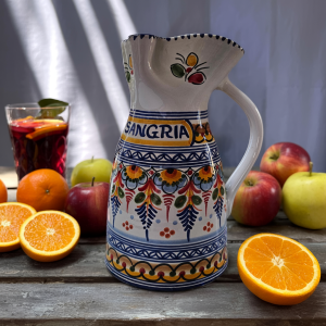 Hand-painted blue sangria pitcher from Spain surrounded by fresh fruit and a glass of sangria.